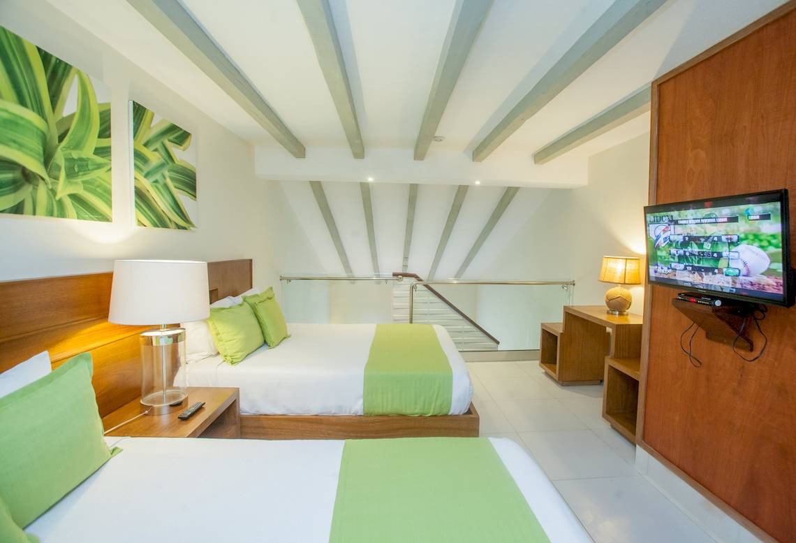 Doppelzimmer im Vista Sol Punta Cana Beach Resort & Spa mit zwei Betten, Fernseher und Lampen.