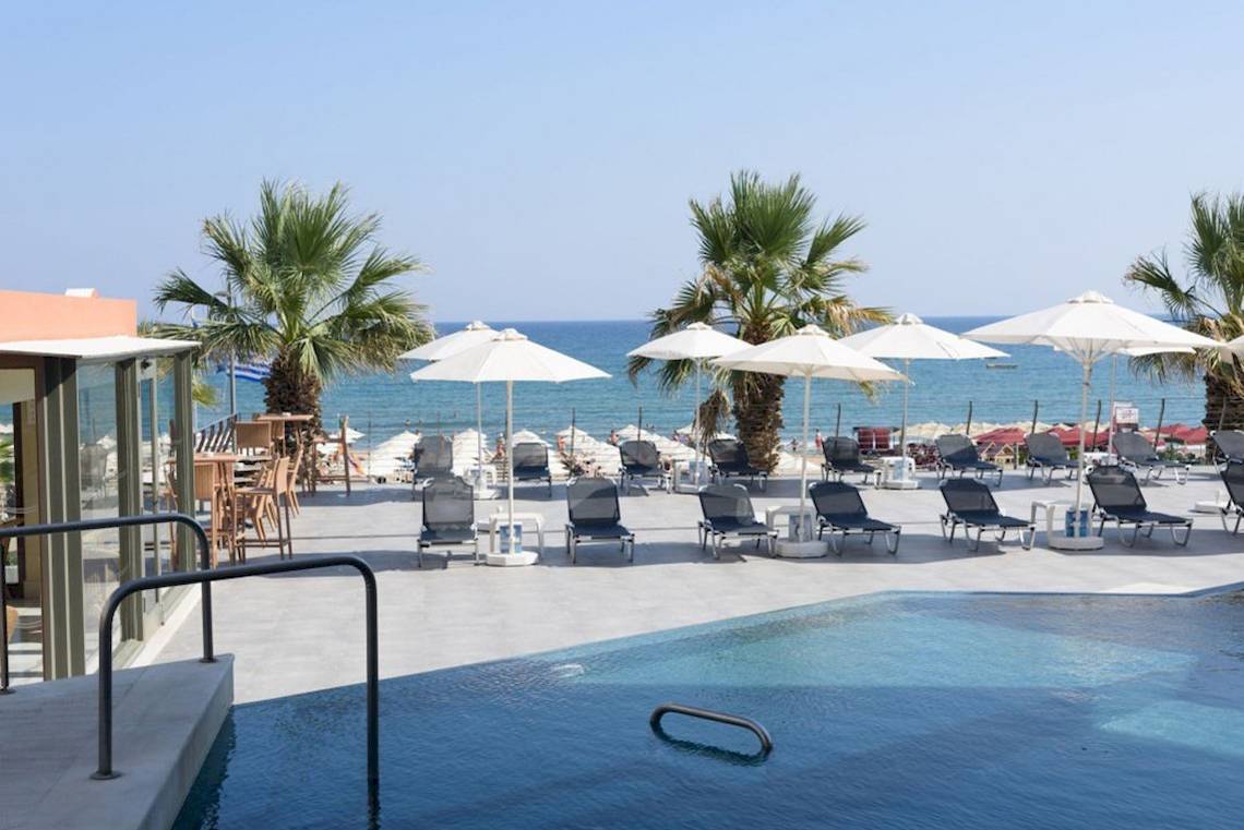 Außenpool und Liegestühle am Strand des Aquila Porto Rethymno Hotels