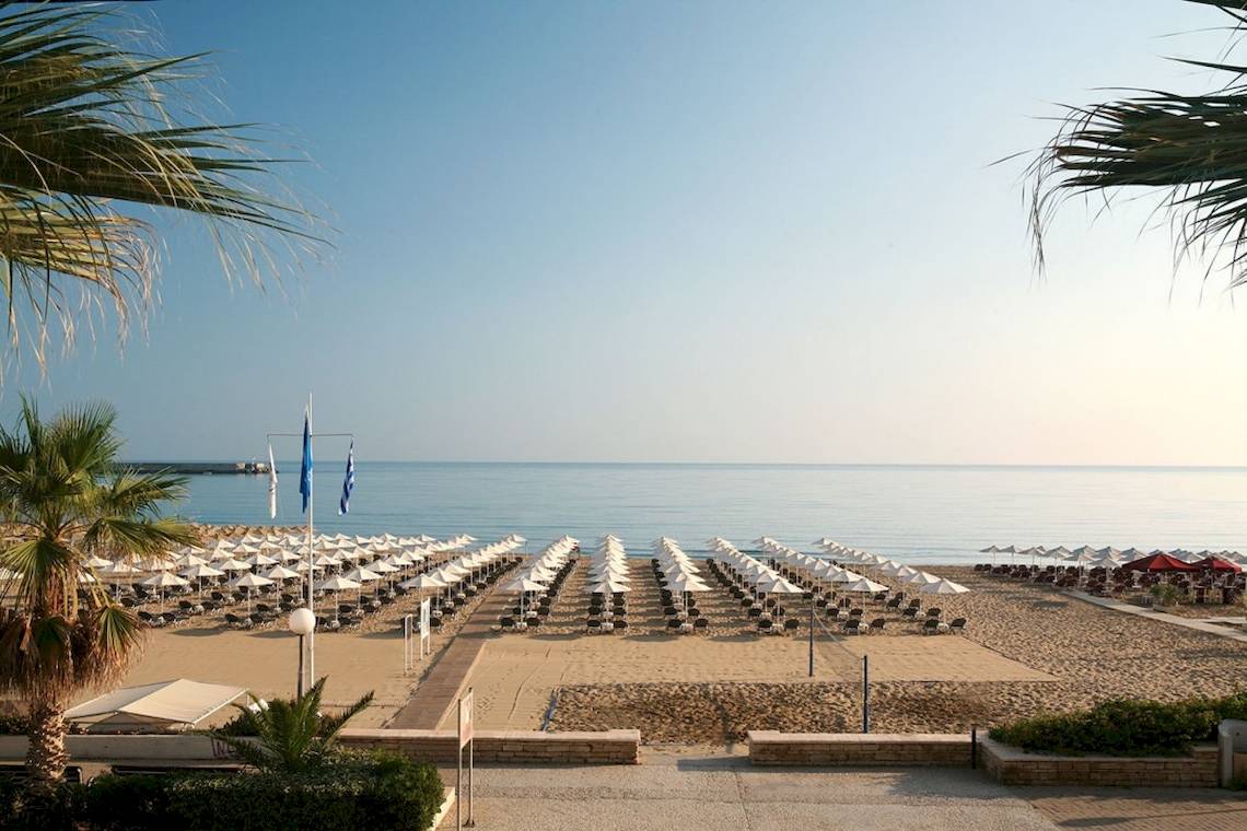 Strandansicht des Aquila Porto Rethymno Hotels mit vielen Sonnenschirmen und Liegestühlen