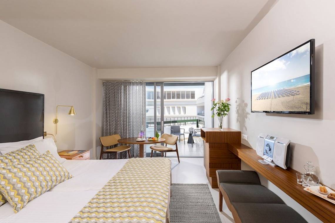Innenansicht eines modernen Hotelzimmers von Aquila Porto Rethymno mit Blick auf die Terrasse und das Meer.