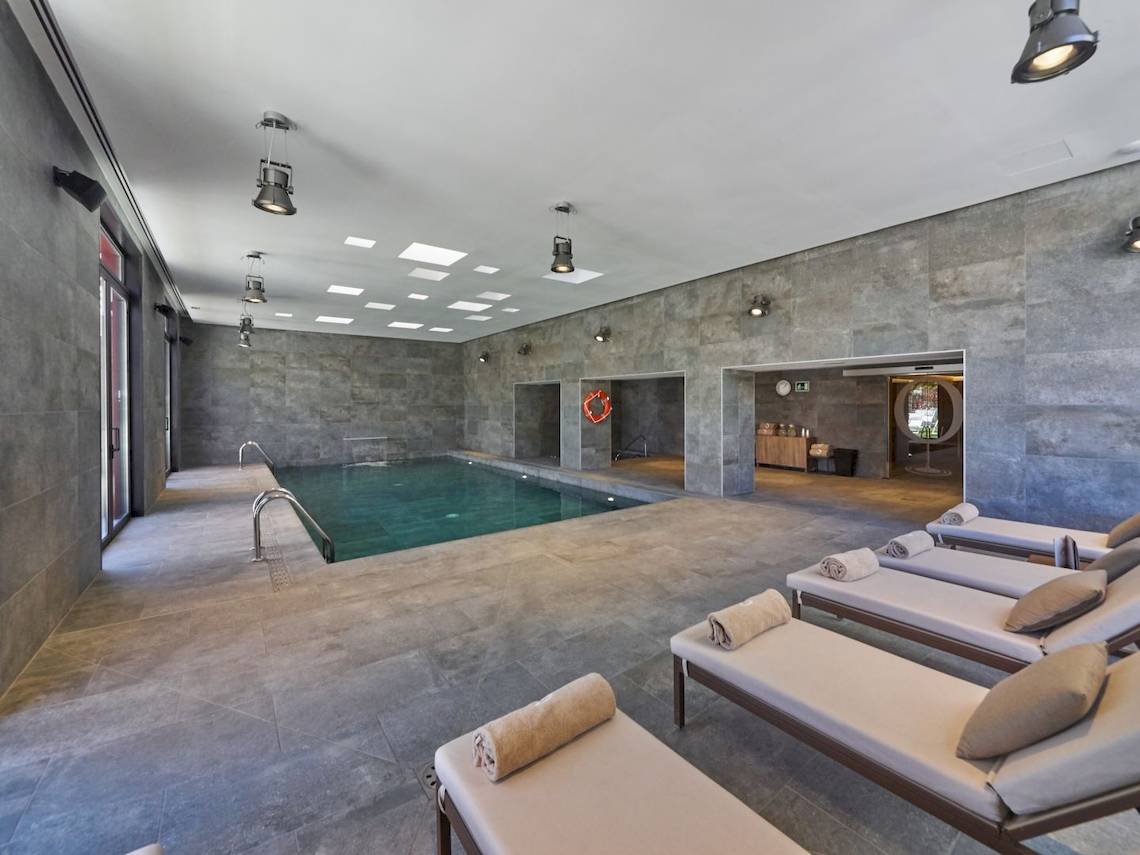 Innenansicht des Schwimmbereichs im Pure Salt Garonda Hotel mit grünem Wasser und Lounge-Liegen.