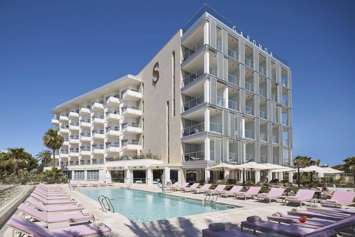 Außenbereich des Pure Salt Garonda Hotels mit Swimmingpool und Loungeliegen
