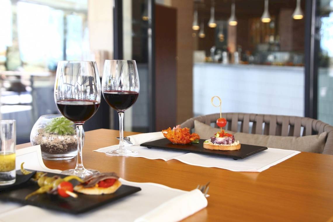 Speisetisch im Pure Salt Garonda Hotel mit Wein und Happen auf schwarzen Tellern.