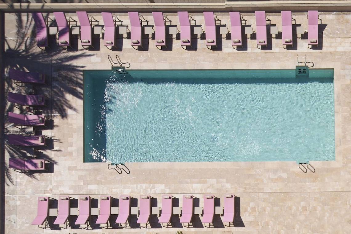 Oberflächenansicht eines Hotelpools mit vielen pinken Liegestühlen.