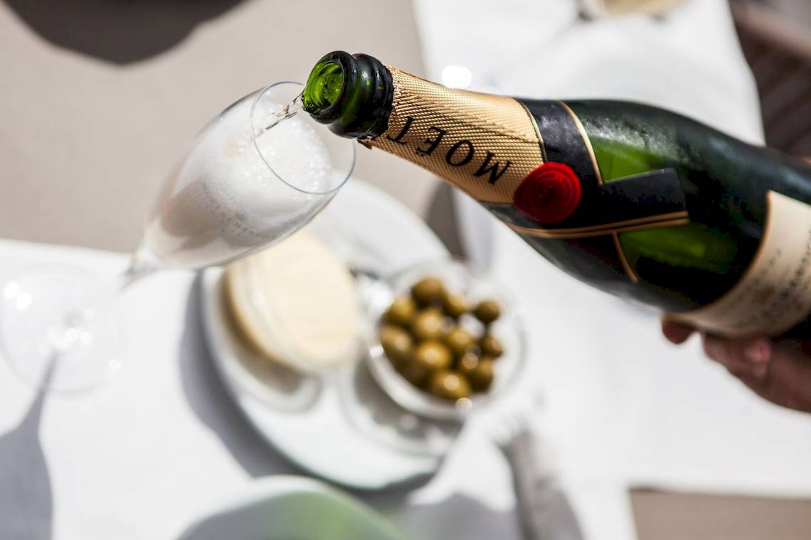 Ein Champagner wird in ein Glas gegossen, serviert mit Oliven und Käse.