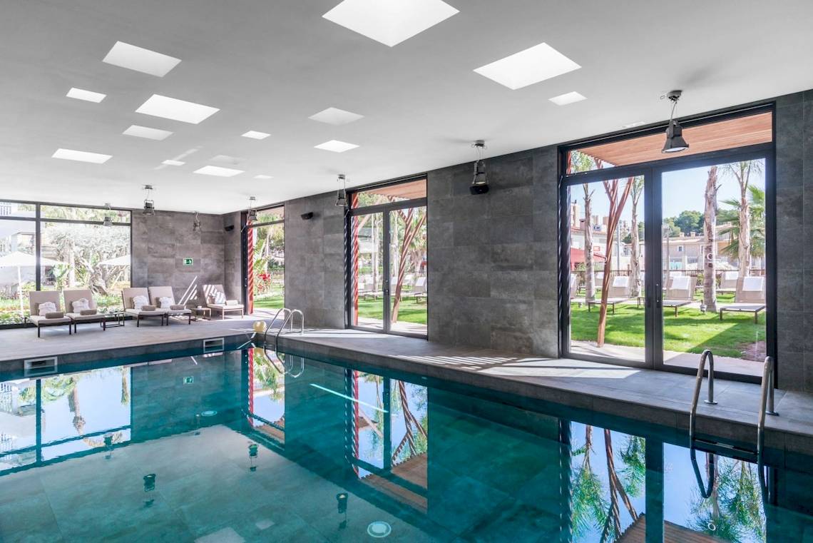 Poolbereich im Pure Salt Garonda Hotel mit Lounge-Sesseln und Glastüren