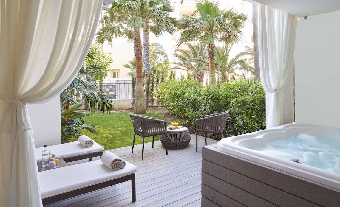 Terrasse des Pure Salt Garonda Hotels mit Whirlpool, Liegen und Tischen im Freien.