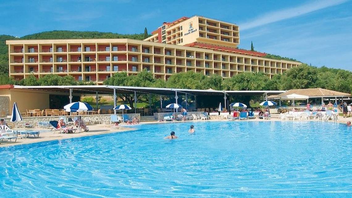 Außenbereich des Atlantica Nissaki Beach Hotels mit Swimmingpool, Sonnenliegen und Gästen.