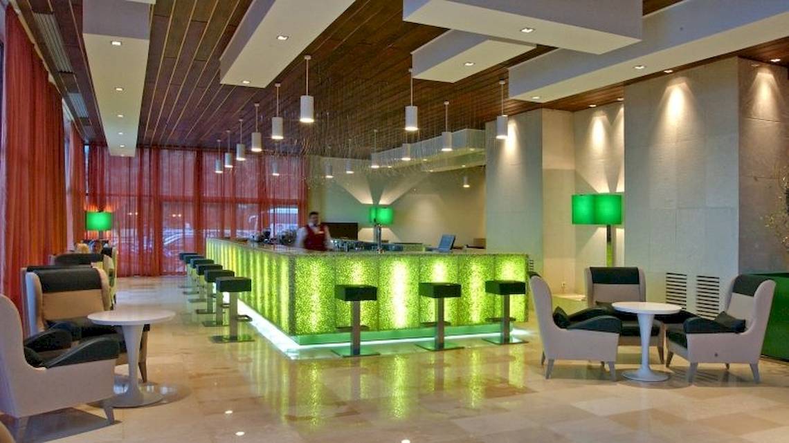 Lobby des Atlantica Nissaki Beach Hotels mit grüner Theke und modernen Möbeln.