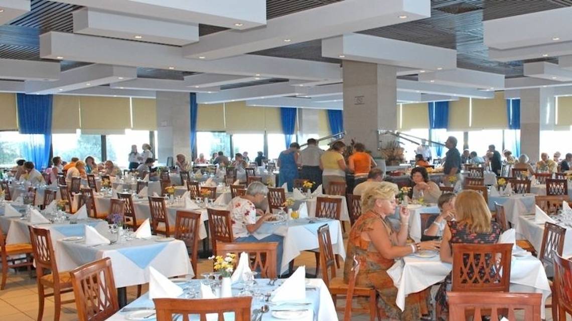 Gäste sitzen in einem großen Restaurant des Atlantica Nissaki Beach Hotels.
