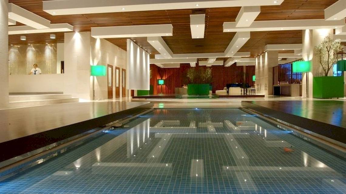 Innenpool des Atlantica Nissaki Beach Hotels mit modernen Leuchten und blauen Fliesen.
