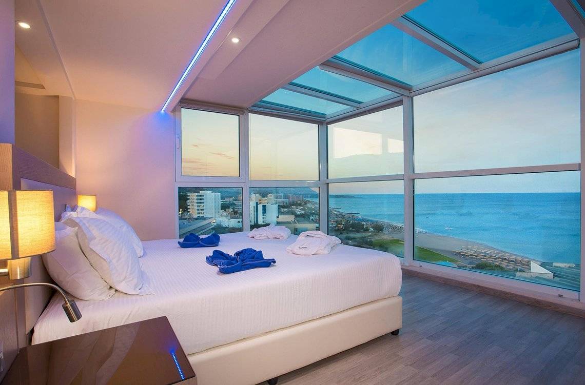 Zimmer im Pegasos Deluxe Beach Hotel mit Blick auf das Meer und eine Stadt.