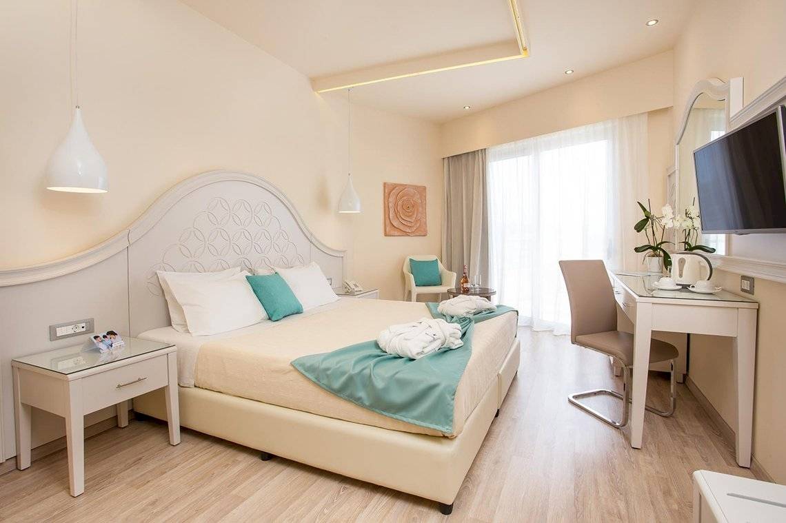 Ein modernes Hotelzimmer mit einem Bett, zwei Nachttischen, einem Schreibtisch und einem Fernseher.