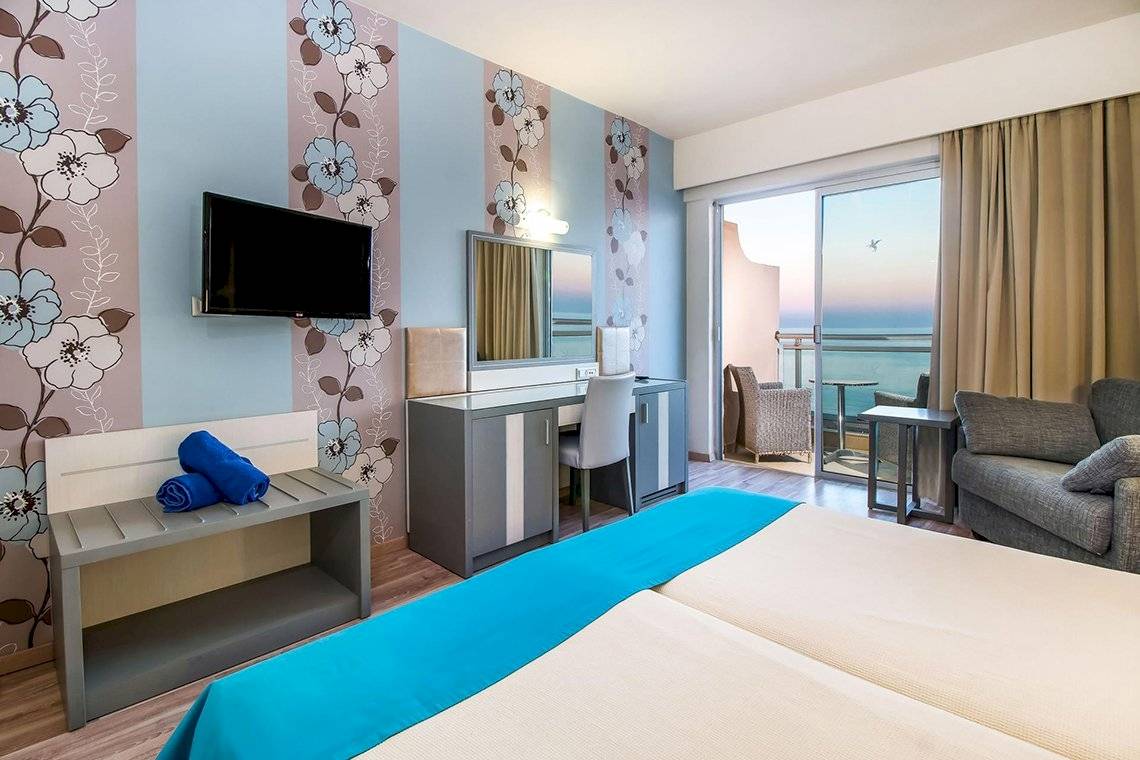 Zimmer im Pegasos Deluxe Beach Hotel mit Meerblick, Fernseher und komfortablen Möbeln.