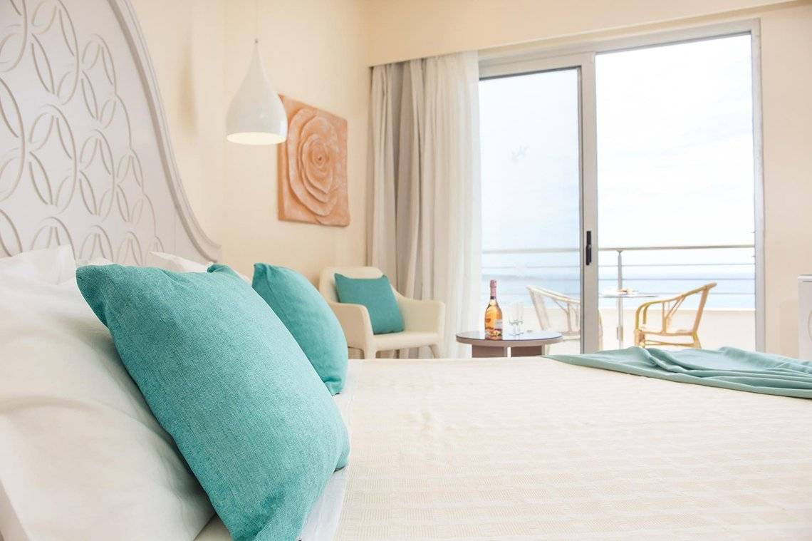 Schlafzimmer im Pegasos Deluxe Beach Hotel mit Meerblick und Balkon.