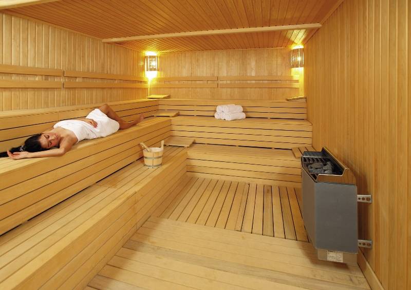 Eine Frau liegt entspannt in einer holzbeplankten Sauna des Radisson Blu Resort & Spa in Cesme.
