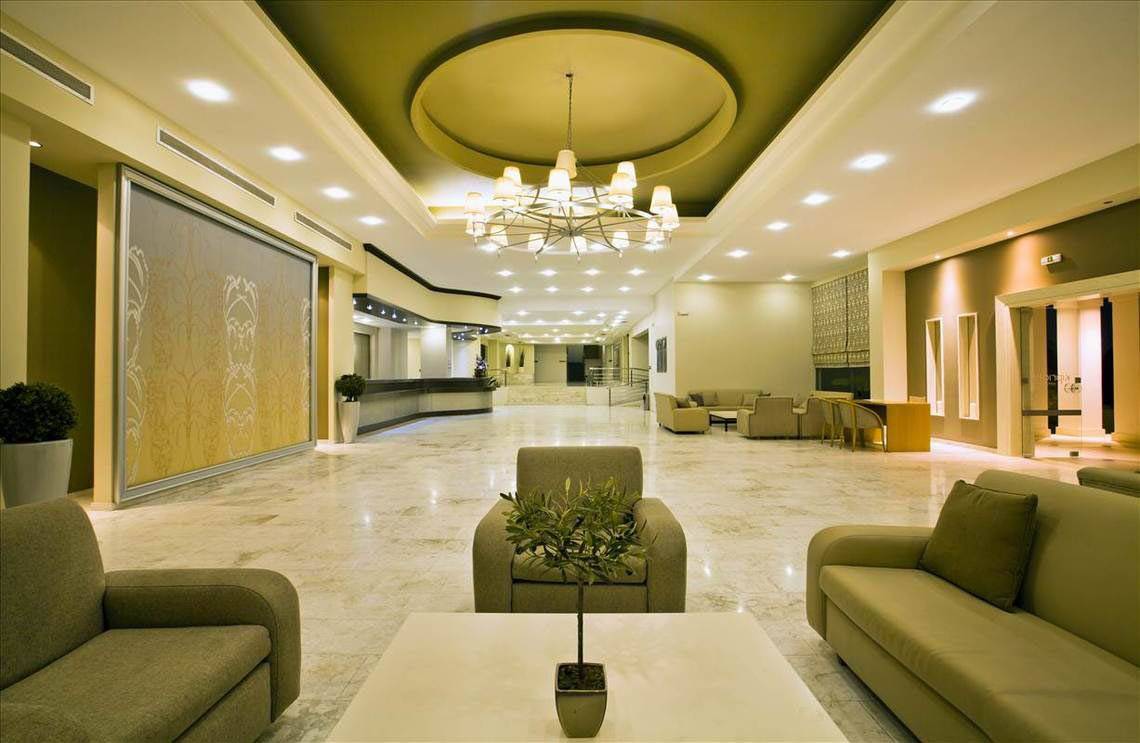 Lobby des Kipriotis Hippocrates Hotels mit Marmorboden, Couchen, und einer Pflanze auf dem Tisch.