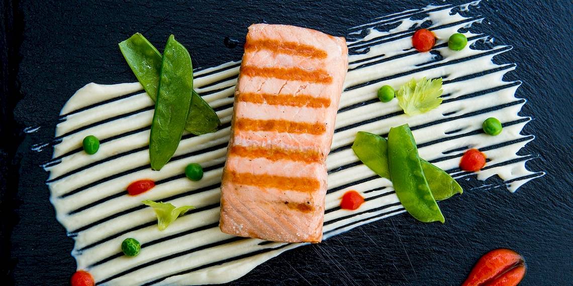 Gegrillter Lachs auf schwarzem Teller mit Gemüse