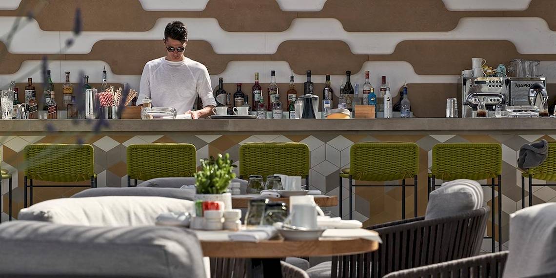 Mitarbeiter arbeitet hinter der Bar im Myconian Naia Hotel