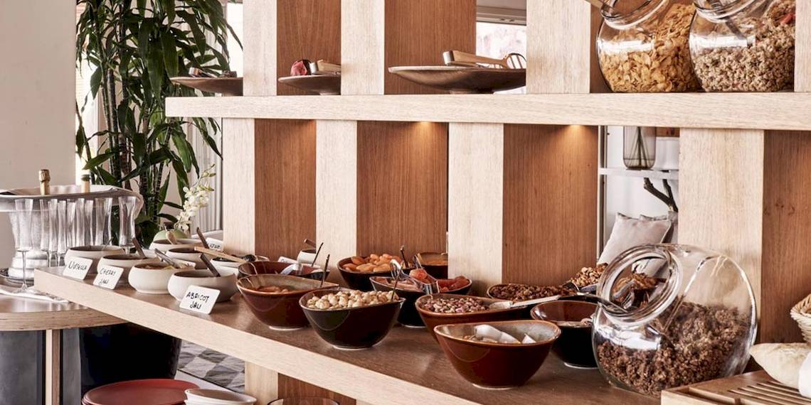 Frühstücksbuffet im Myconian Naia Hotel mit verschiedenen Schüsseln und Gläsern.