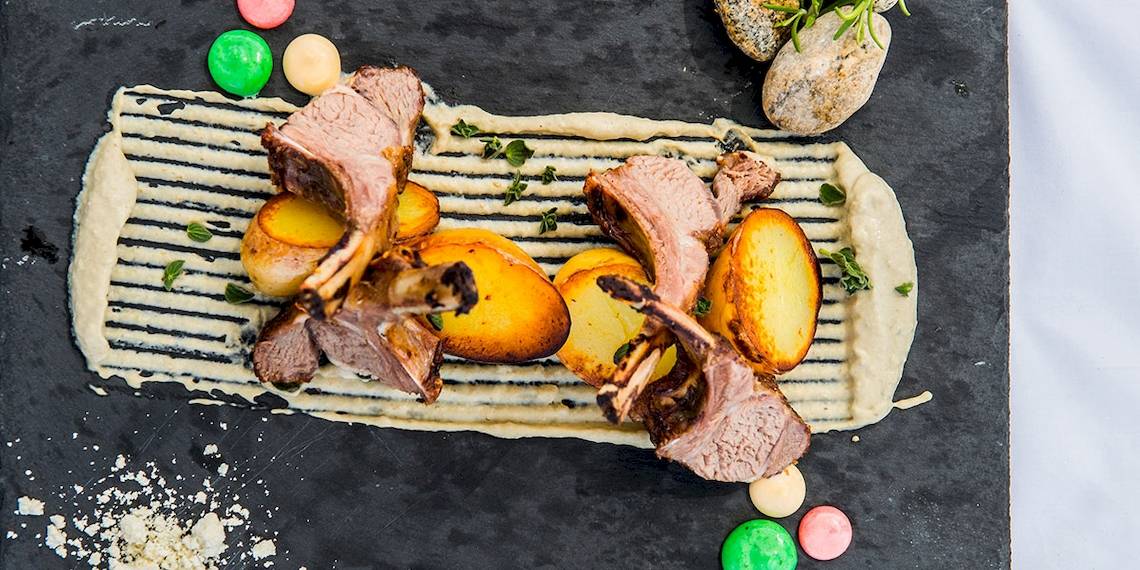 Lammkoteletts und Kartoffeln auf einer schwarzen Platte im Myconian Naia Hotel