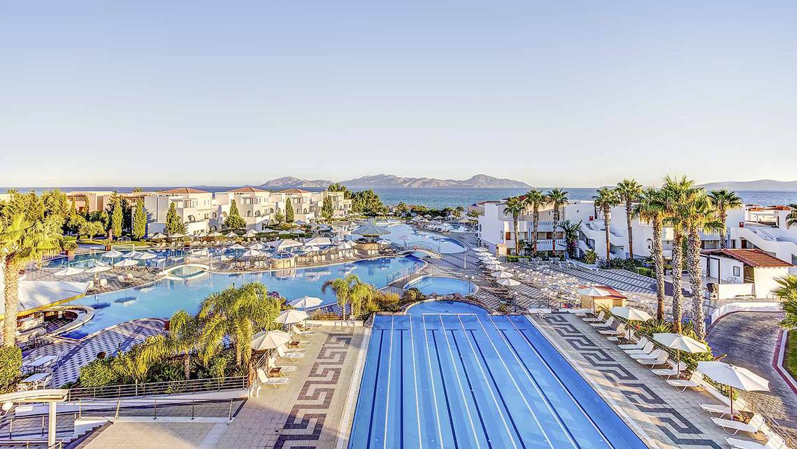 Außenansicht des Atlantica Marmari Palace Resorts mit Pools, Sonnenliegen und Palmen.