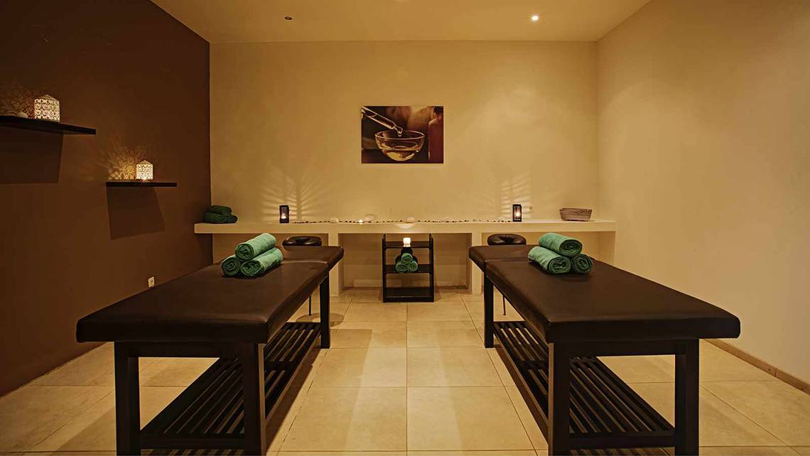 Massage-Salon im Atlantica Marmari Palace mit zwei Massagetischen und grünen Handtüchern.