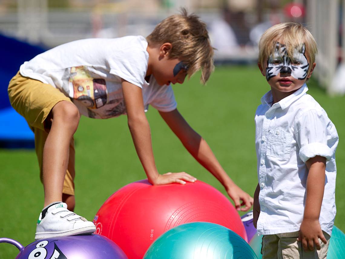 Zwei junge Jungs mit Tiermasken auf einem Spielplatz, einer mit einer Tigermaske und der andere mit einer schwarzen Maske.