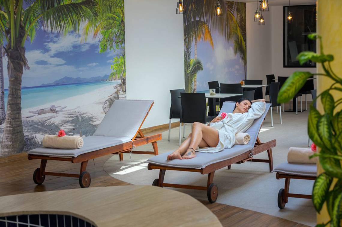 Eine Frau liegt auf einer Liege im Loungebereich des Cavo Maris Beach Hotels.