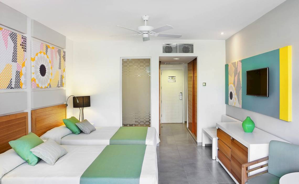 Zwei Betten mit grünen Kissen in einem modernen Zimmer im Playa Vista Azul Varadero Hotel.