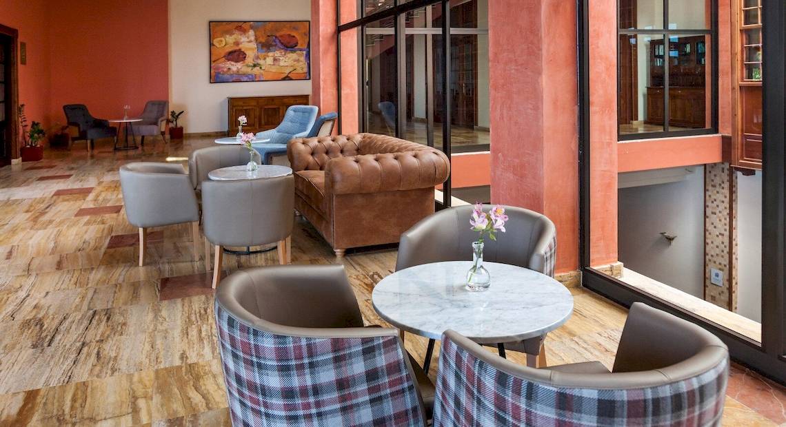 Hotel-Lounge-Bereich im Occidental Jandia Royal Level mit braunem Sofa und mehreren Sesseln um einen Tisch.
