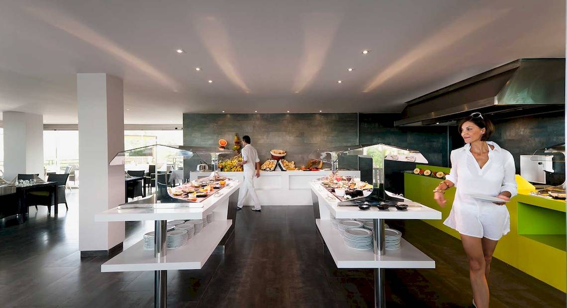 Ein Buffetbereich im Occidental Jandia Royal Level Hotel mit einer Frau und einem Mann, servieren Essen.