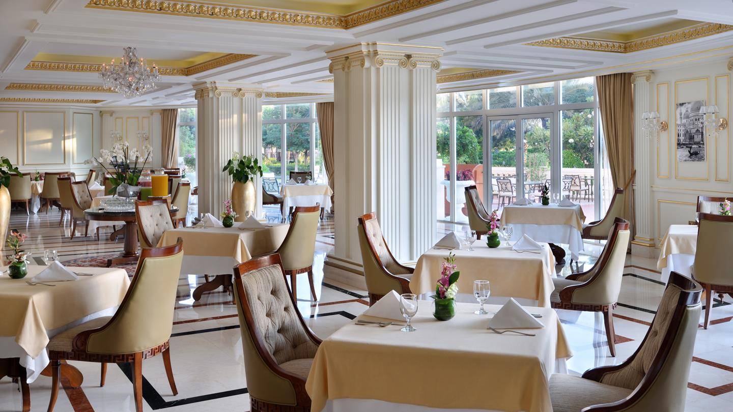 Innenansicht des Restaurants im Kempinski Hotel Residenzen Palm Jumeirah mit eleganten Tischen, Stühlen und Blumenarrangements.