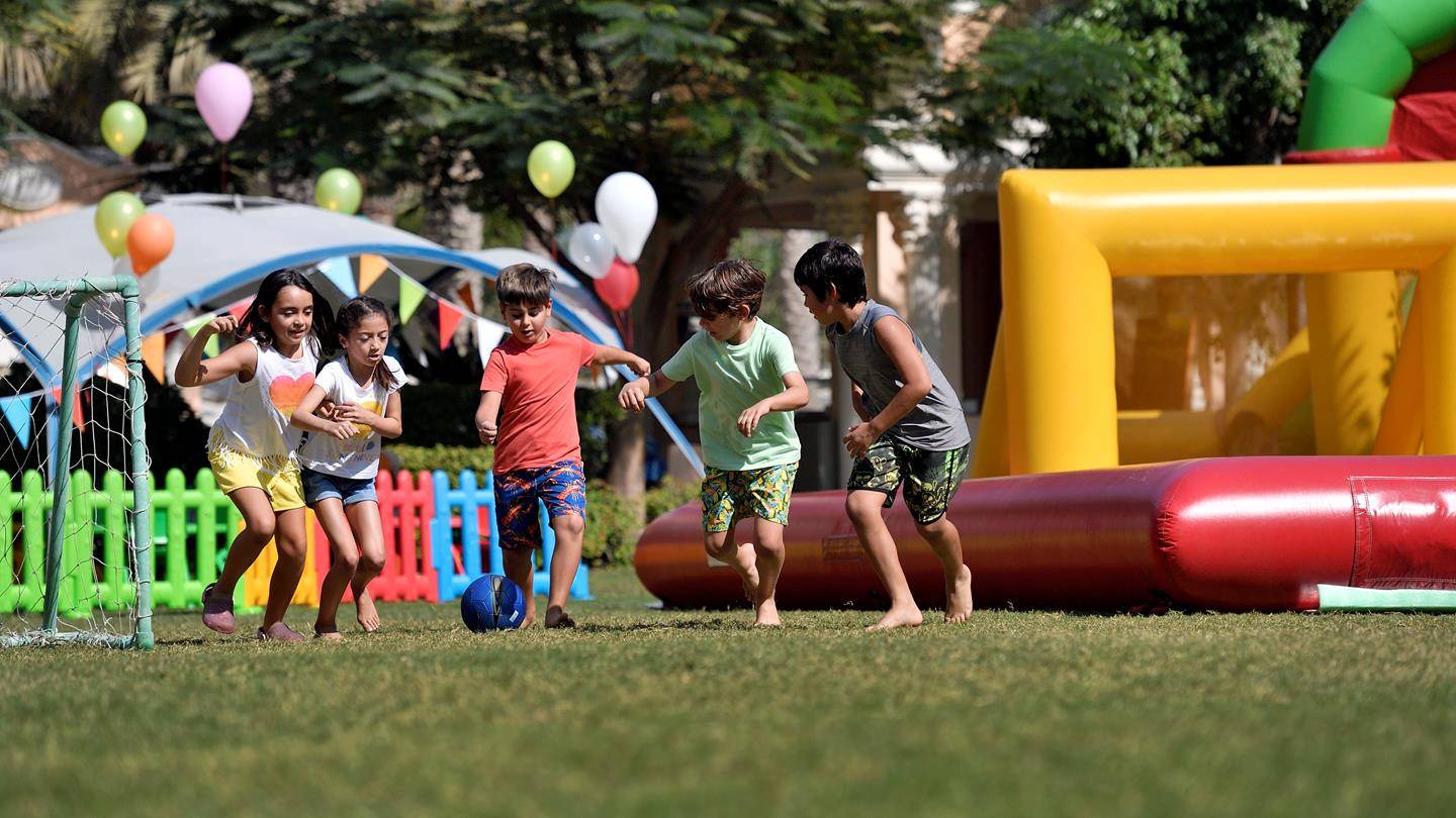 Kinder spielen auf einer Rasenfläche im Freizeitpark des Kempinski Hotel Residences Palm Jumeirah.