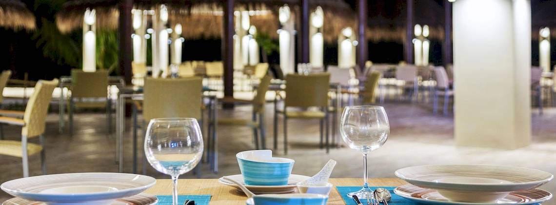 Abendessen im Cocoon Maldives Hotel Restaurant mit gedeckten Tischen und Stühlen.