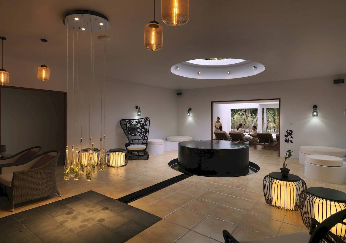 Innenbereich des Cocoon Maldives Hotels mit Loungebereich, Couch und Lichtinstallationen.