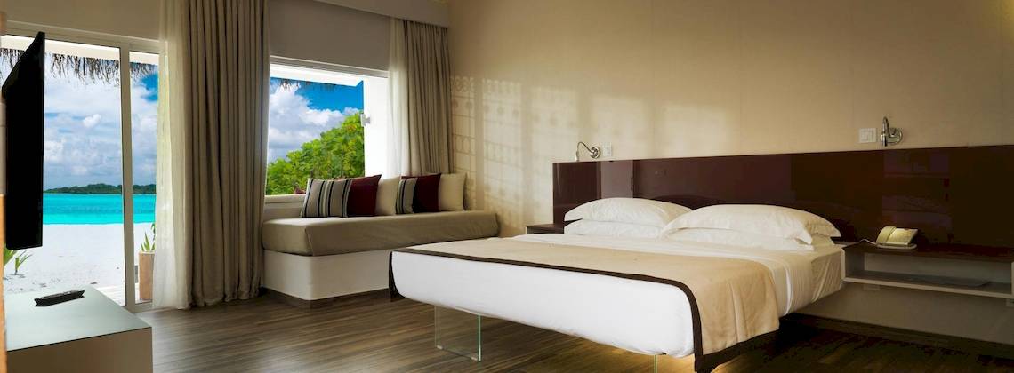 Innenansicht eines Cocoon Maldives Hotelzimmers mit Meerblick und moderner Einrichtung.