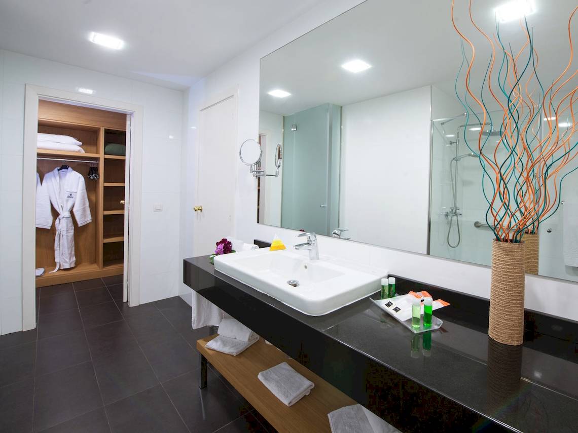 Badezimmer im Fuerteventura Princess Hotel mit weißem Waschbecken, Spiegel und blauen Dekorationselementen.