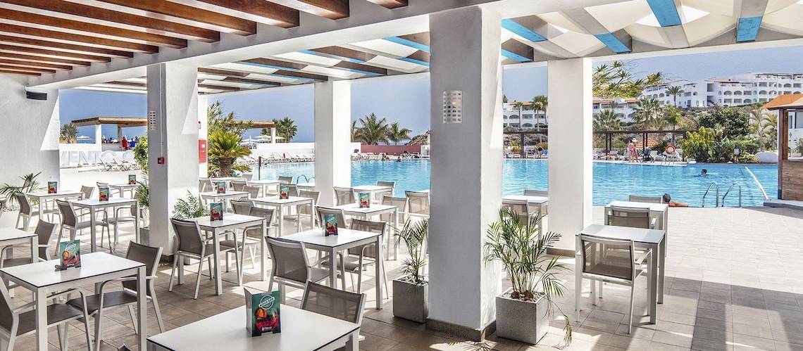 Restaurantbereich mit Tischen und Stühlen neben einem Swimmingpool im Fuerteventura Princess Hotel.