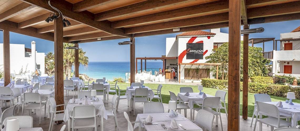 Außenbereich des Fuerteventura Princess Hotels mit Tischen und Stühlen, Blick auf das Meer.