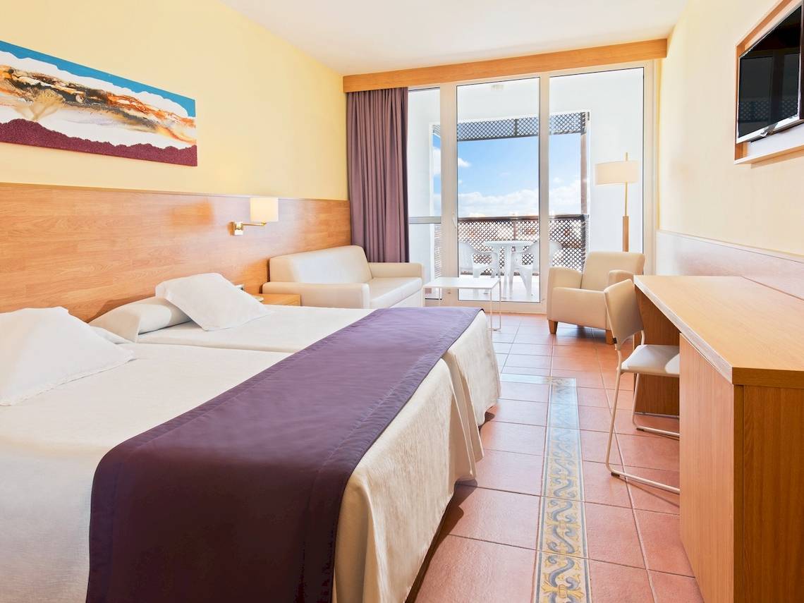 Doppelzimmer im Fuerteventura Princess Hotel mit zwei Betten, Blick auf die Terrasse und Möbeln.