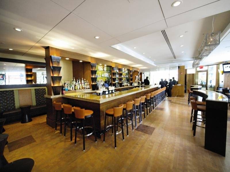 Die Bar im New Yorker Hotel mit gepolsterten Stühlen und einer Theke voller Flaschen.