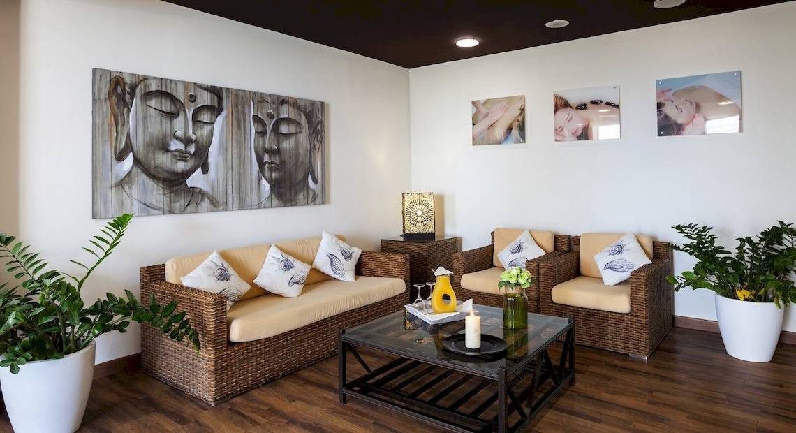 Ein Hotel-Lounge-Bereich mit zwei Sofas, Kissen, einem Tisch, Pflanzen und Gemälden an der Wand.