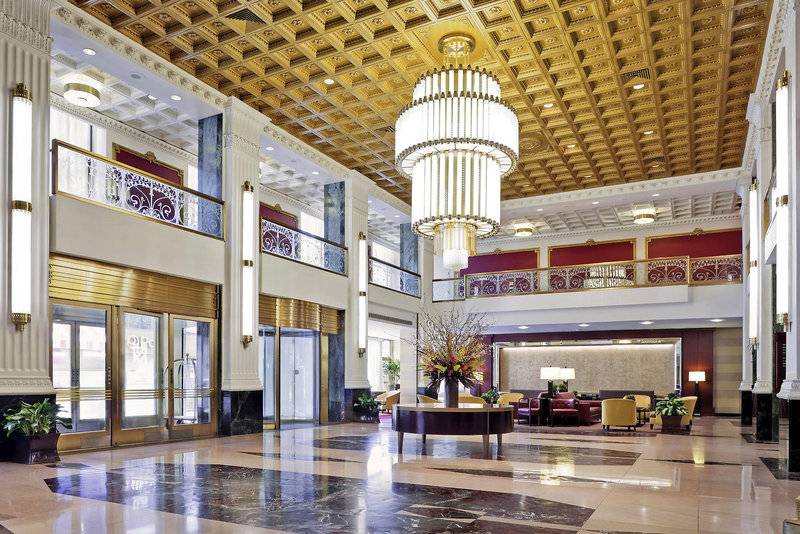 Die Lobby des New Yorker Hotels mit goldener Decke und Kronleuchter.