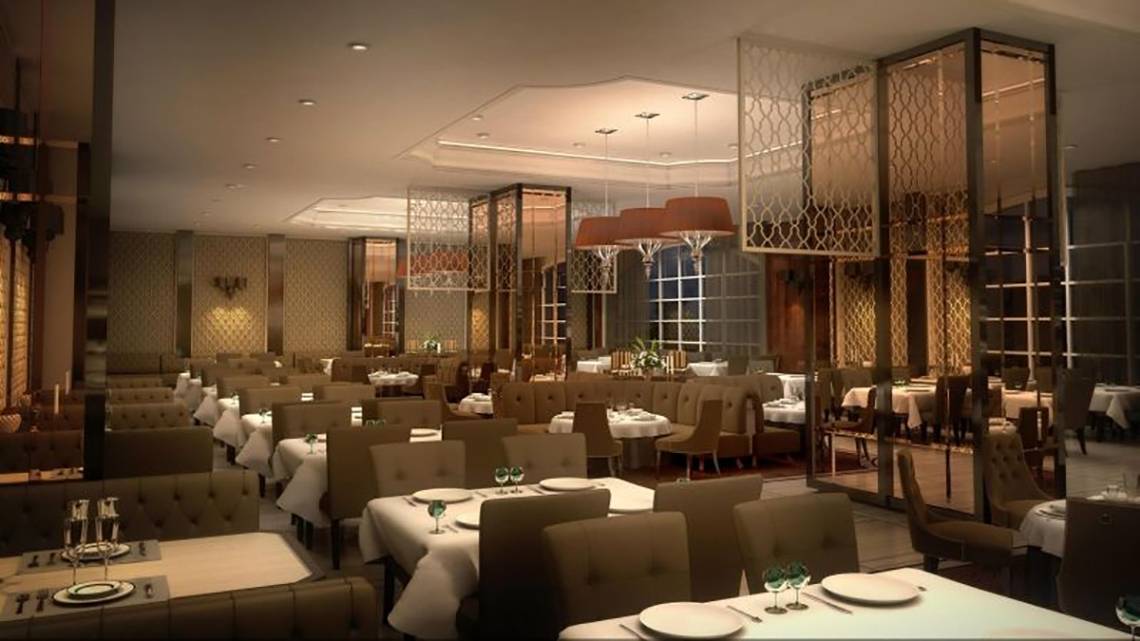 Innenansicht des Restaurants im Vogue Hotel Supreme Bodrum mit runden Tischen und Stühlen, goldenen Kronleuchtern und gemusterten Trennwänden.