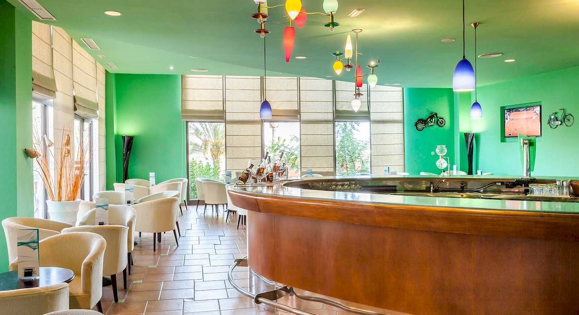 Innenbereich der Bar im Occidental Jandia Royal Level Hotel mit grünen Wänden und Holzbar.