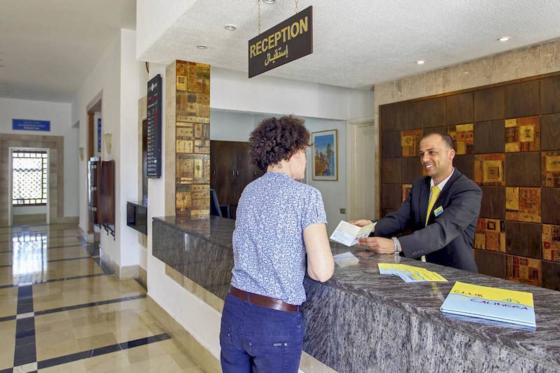 Ein Rezeptionsmitarbeiter hilft einem Gast im Hotel Calimera Yati Beach.