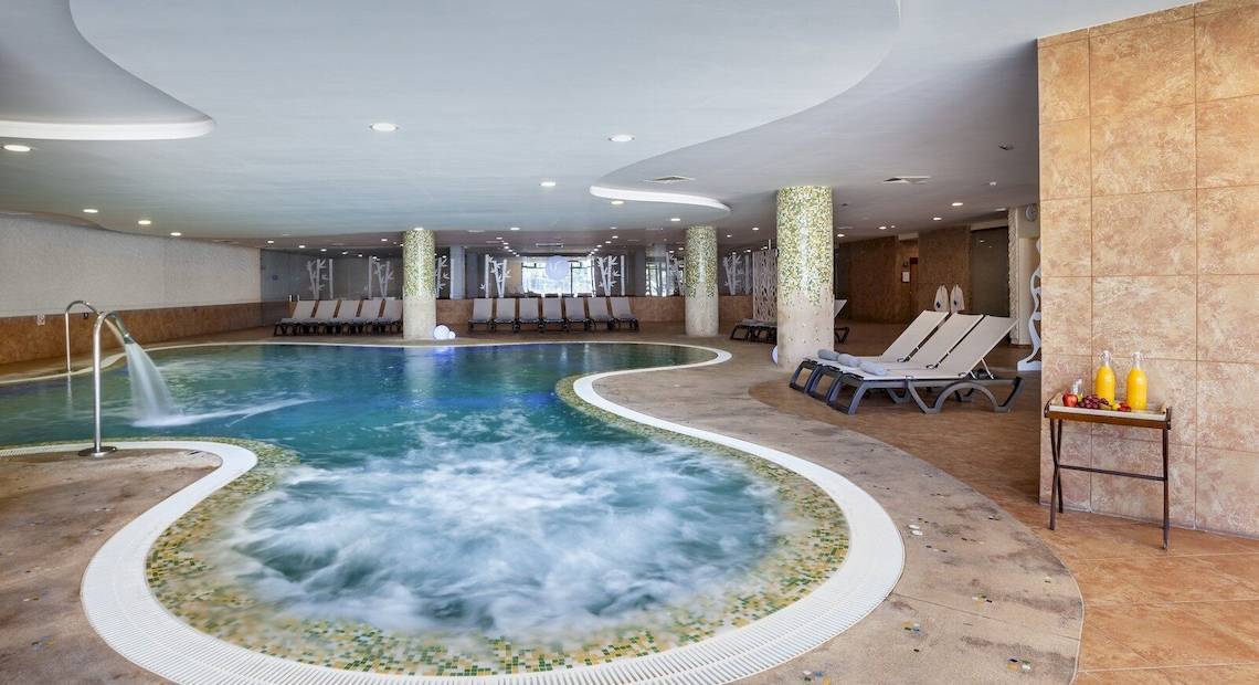 Innenpool im Occidental Jandia Mar Hotel mit Lounge-Liegestühlen und Wasserspender.