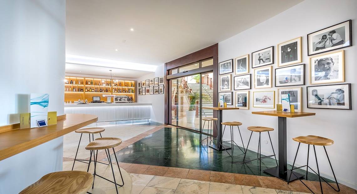 Innenansicht der Bar im Occidental Jandia Mar Hotel mit Tischen, Stühlen und Fotowänden.