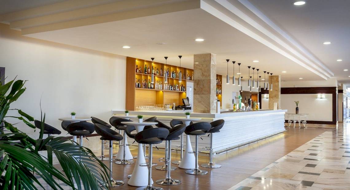 Innenansicht der Bar im Occidental Jandia Mar Hotel mit Barhockern, Theke und Pflanzen.